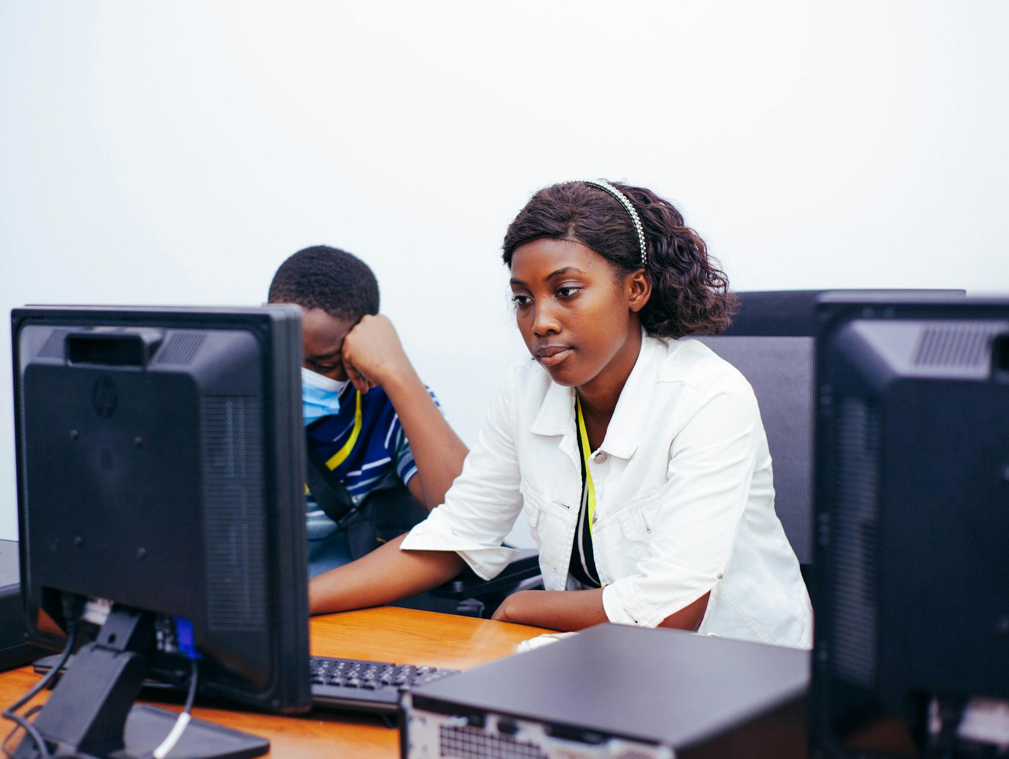 Two young professionals focused on their computer screens, collaborating in a modern office setting.